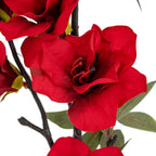 Close-up of an open crimson bloom with curved petals, dark tips at its centre and brown branches crossing behind it.