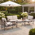 Lounge seating arranged around a table styled with tableware and a jug on a paved garden terrace beneath a white parasol.