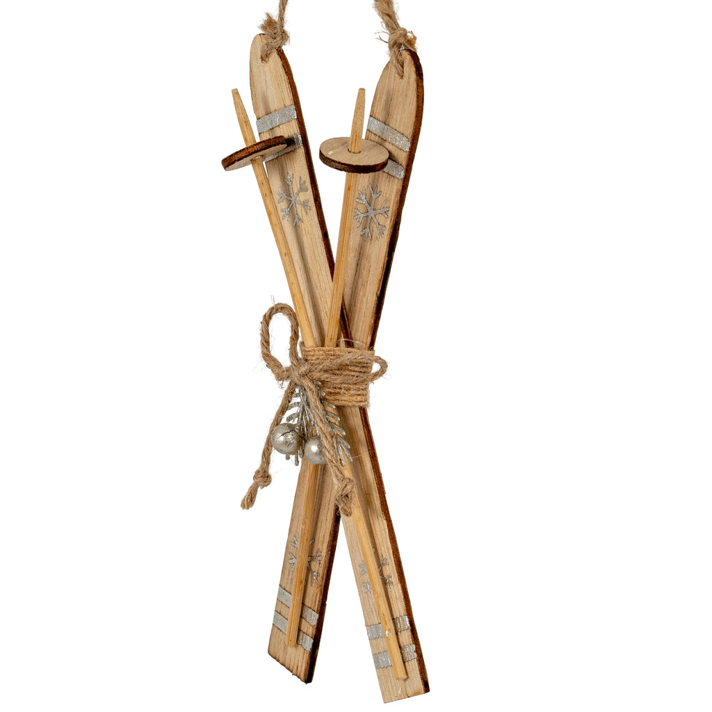Angled view of the crossed-ski ornament showing darker edges, slender pole forms with circular discs and silver-coloured stripes near the ends.