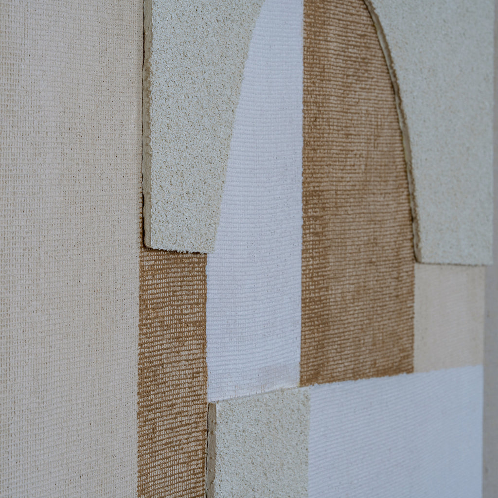 Close-up of raised granular cream panels beside white woven-looking areas and ochre-brown crosshatching around the central arch.