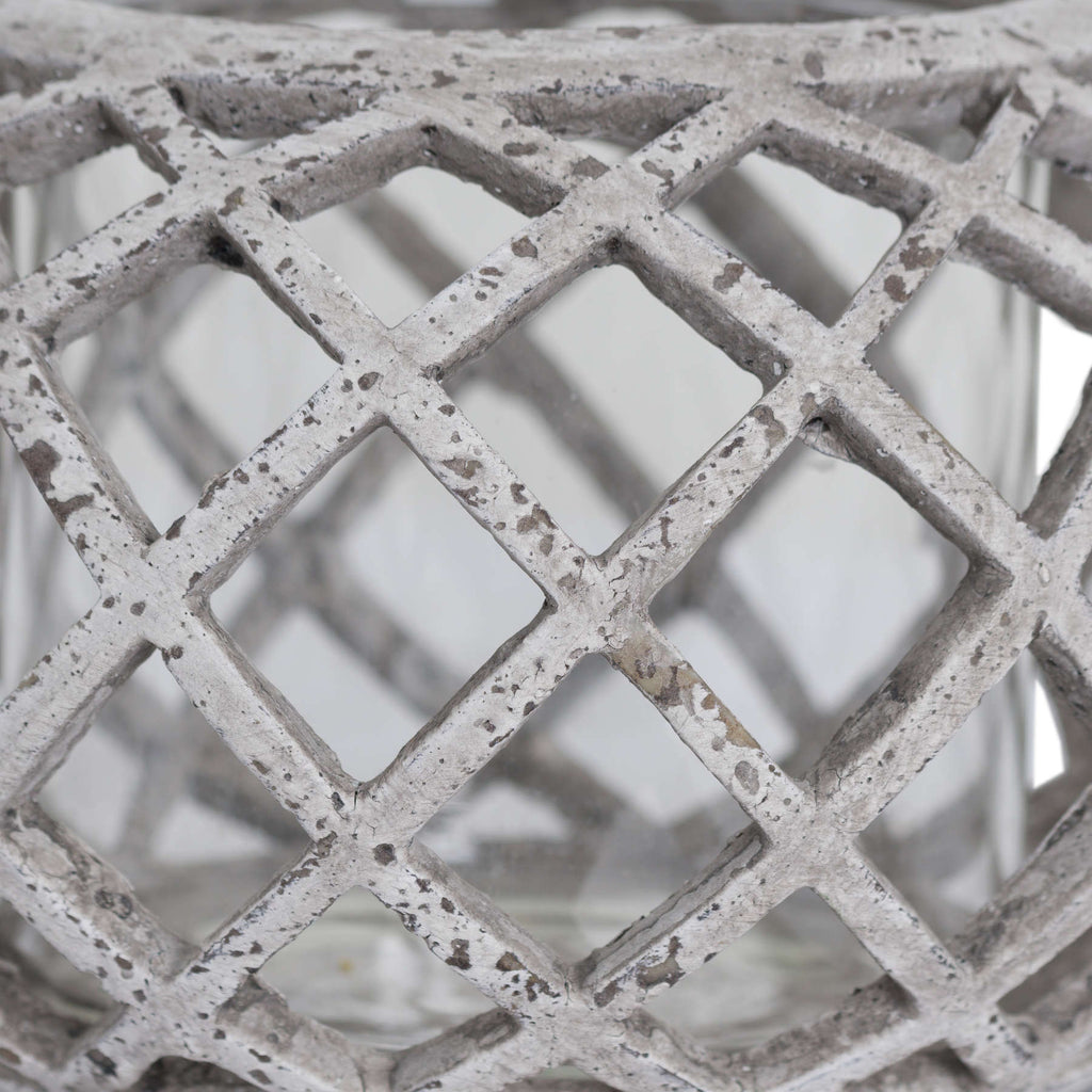 Close-up of the lantern's crossing lattice ribs, with dark speckles and distressed markings across the pale finish.
