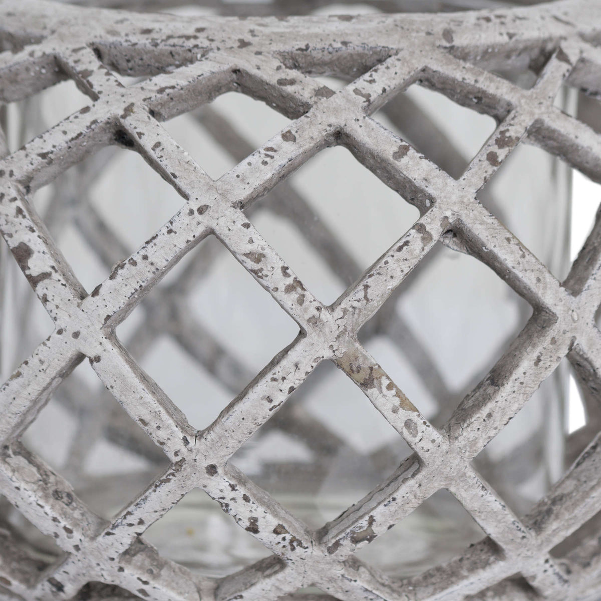 Close-up of the lantern's crossing lattice ribs, with dark speckles and distressed markings across the pale finish.