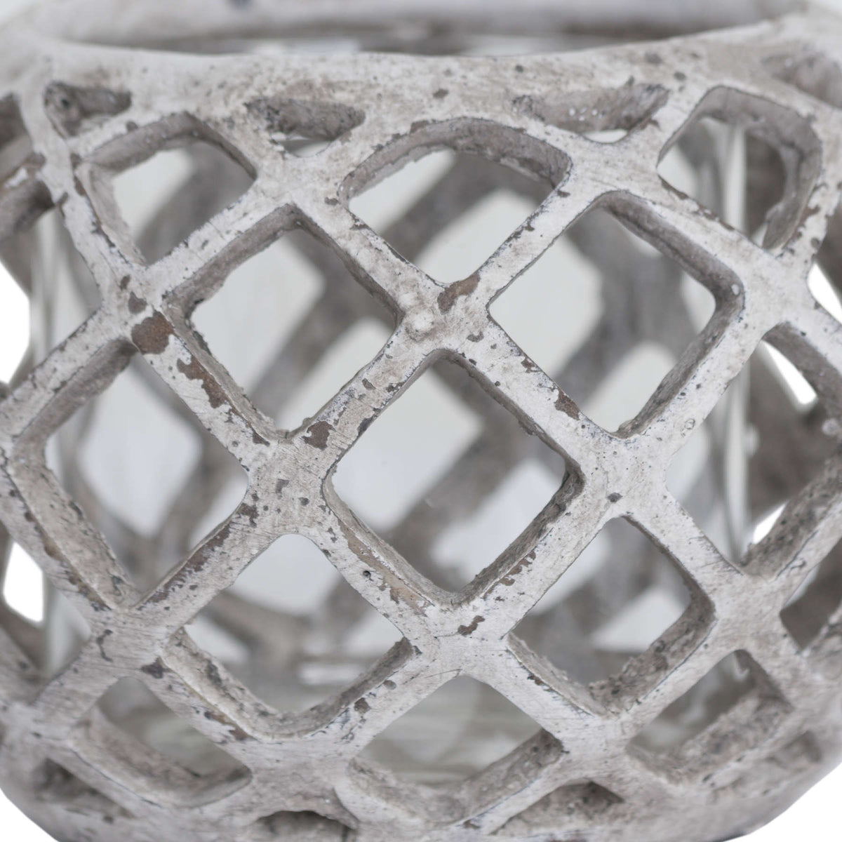 Close-up of the lantern's criss-cross lattice, with rounded diamond openings and darker patches across the distressed pale surface.