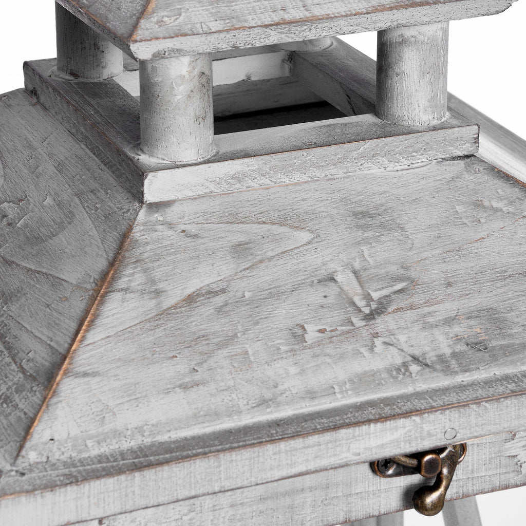 Close view of the lantern's pitched roof and open upper tier, showing the rubbed grey wood finish and bronze-toned front catch.