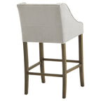 Rear angled view of the Crossstitch Counter Stool, with a plain pale back, piped curved sides and rectangular stretchers between brown legs.