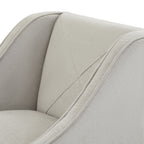Close-up of the stool's pale textured covering, diagonal back stitching and piping along the curved arm.