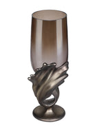Angled view of the hurricane candle holder showing the open glass rim and broad folded curves of the metallic base.