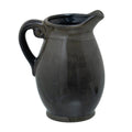 Dark glossy rounded vase on a circular foot, with a curled loop handle on the left and a raised lip on the right.