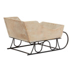 Rear three-quarter view of the decorative sleigh showing its tall back panel, pale grain-like markings and black looped supports.