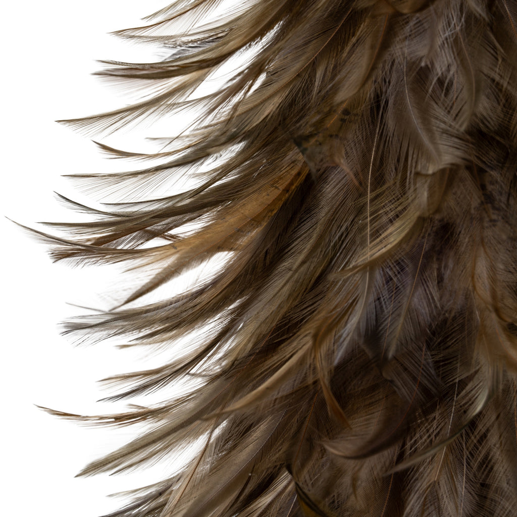 Close-up of the decorative tree's layered feather-like surface, showing fine strands and long curved tips in grey and warm brown.