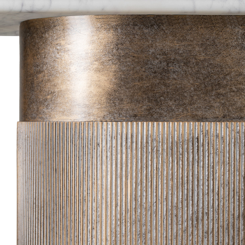 Detail of the champagne gold column beneath the marble top, showing a smooth mottled band above fine vertical fluting.