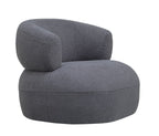 Three-quarter view of the grey bouclé armchair showing the wraparound back and rounded upholstered base.