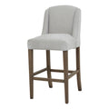 Front three-quarter view of a pale grey bar stool with a curved winged back, brown legs and rectangular lower rails.