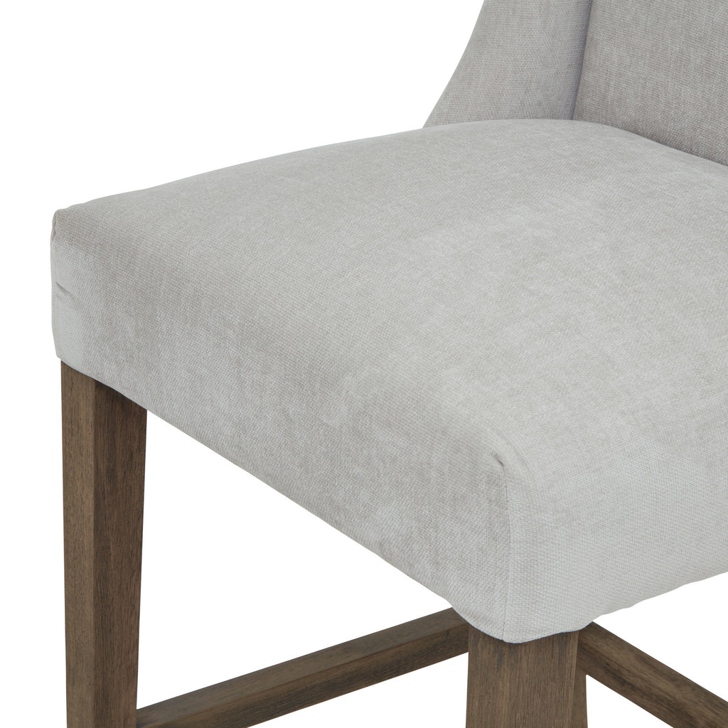 Detail of the pale grey seat's rounded front edge and woven texture above the brown legs and lower rails.