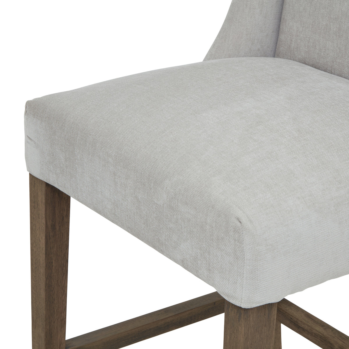 Detail of the pale grey seat's rounded front edge and woven texture above the brown legs and lower rails.