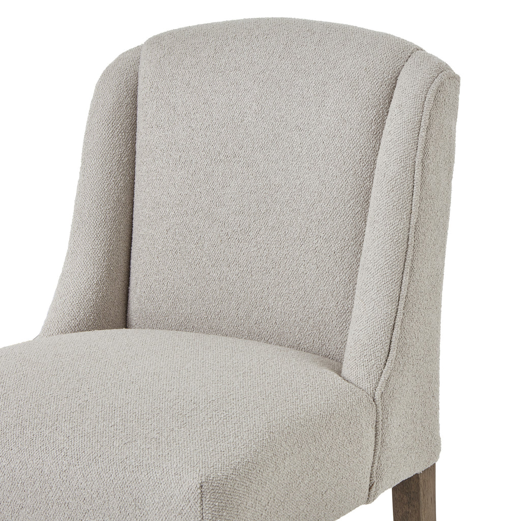 Close view of the chair’s curved upholstered back, defined side wings and rounded seat edge.