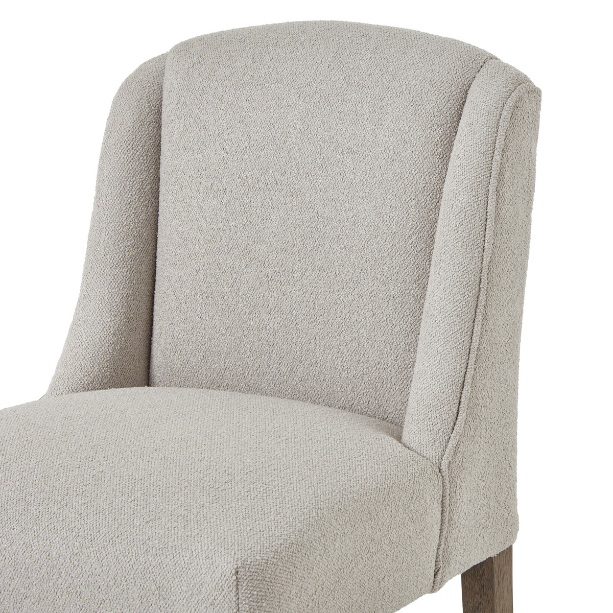 Close view of the chair’s curved upholstered back, defined side wings and rounded seat edge.