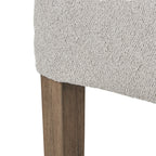 Detail of pale textured upholstery along the seat edge above a brown wooden leg with visible grain.