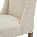 Detail of the cream loop-textured seat meeting the curved side wing, with part of a brown leg visible below.