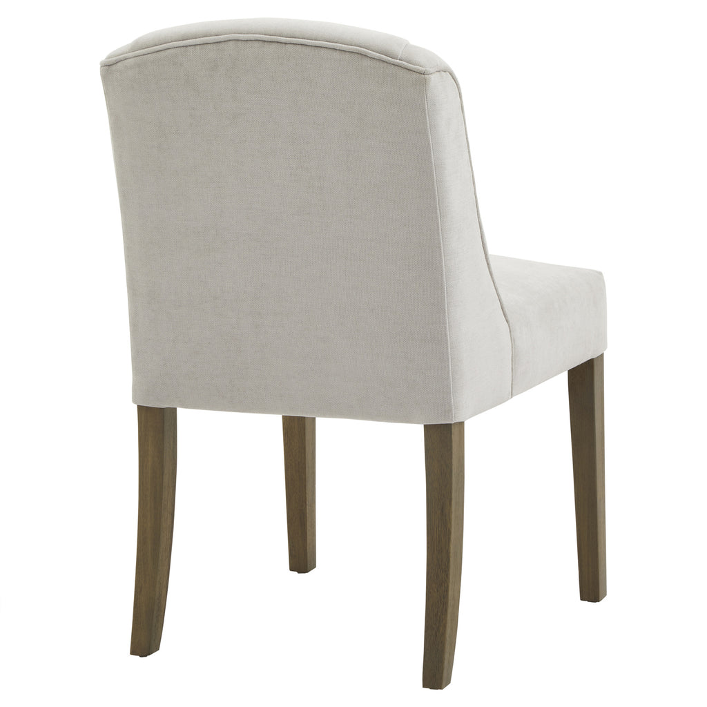 Rear three-quarter view showing the chair's pale grey covered back, piping along its arched top edge and brown legs.