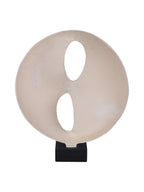 Rear view of the cream sculpture with two organic openings and a recessed surface on a black base.