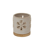 Angled view of the cream candle holder showing open snowflake cut-outs, a rounded rim and a warm-toned patterned base.