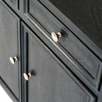 Angled close-up of the sideboard's pale round drawer knob, dark surface texture and layered panel edges, with the door knobs below.