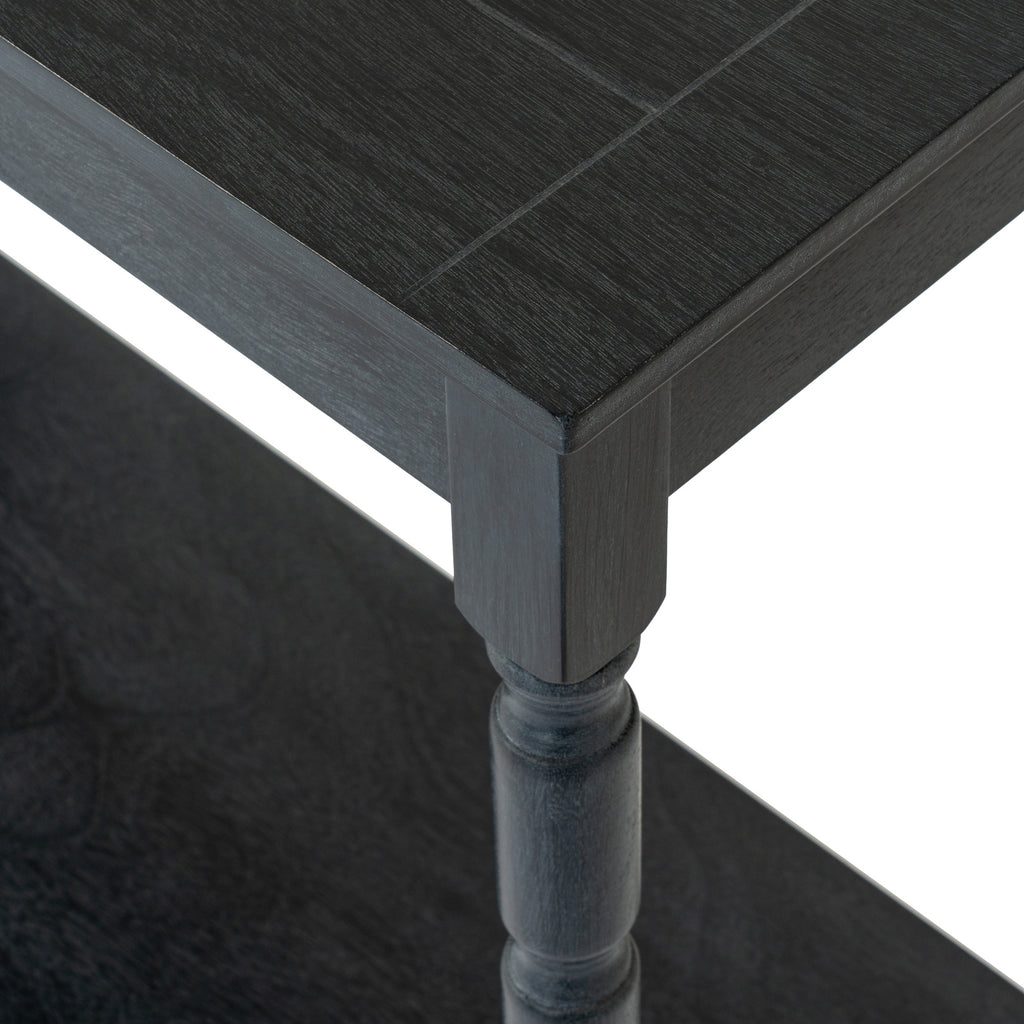 Close-up of the dark console table's top corner and leg, showing fine grain texture, the straight apron and rounded leg profile above the lower shelf.