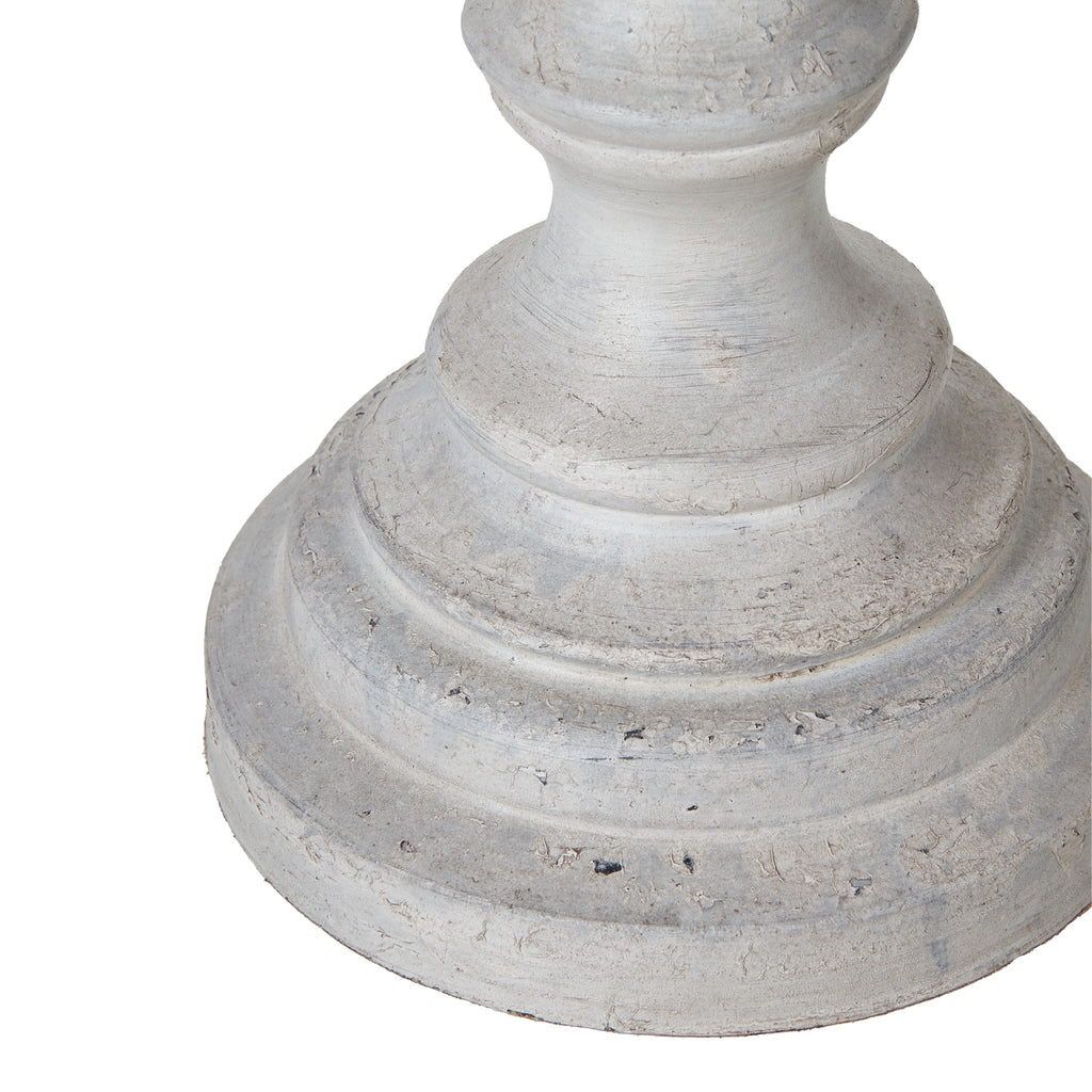 Detail of the lamp's curved lower stem and stepped circular foot with pale grey-white colouring and darker surface marks.