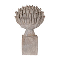 Front view of a pale grey-beige artichoke ornament with brown-tipped upright leaves, a short tapered stem and a rectangular mottled plinth on a white background.