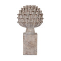 Pale grey-beige artichoke ornament with upright layered leaves, brown tips and a short tapered stem above a tall rectangular plinth, shown against white.