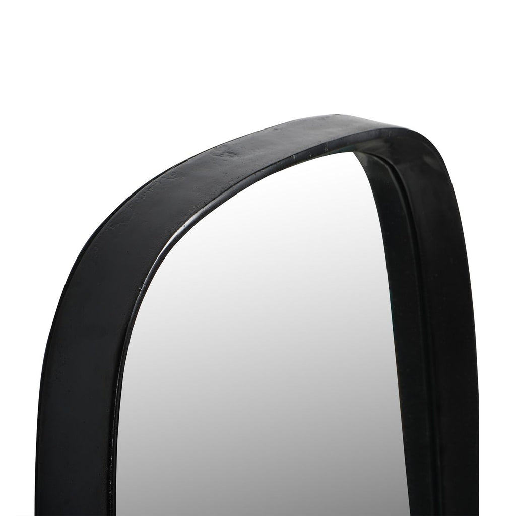 Angled close-up of the mirror's rounded top showing the textured surface and depth of the dark frame.