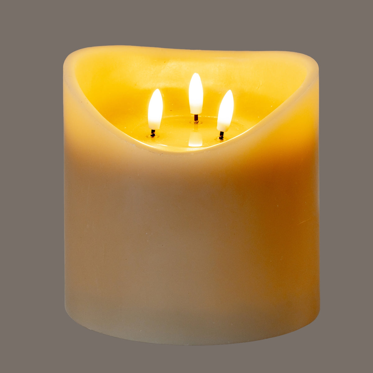 Taupe LED candle photographed illuminated against a grey background, with three bright flame-shaped elements and yellow light visible inside the deep recess.