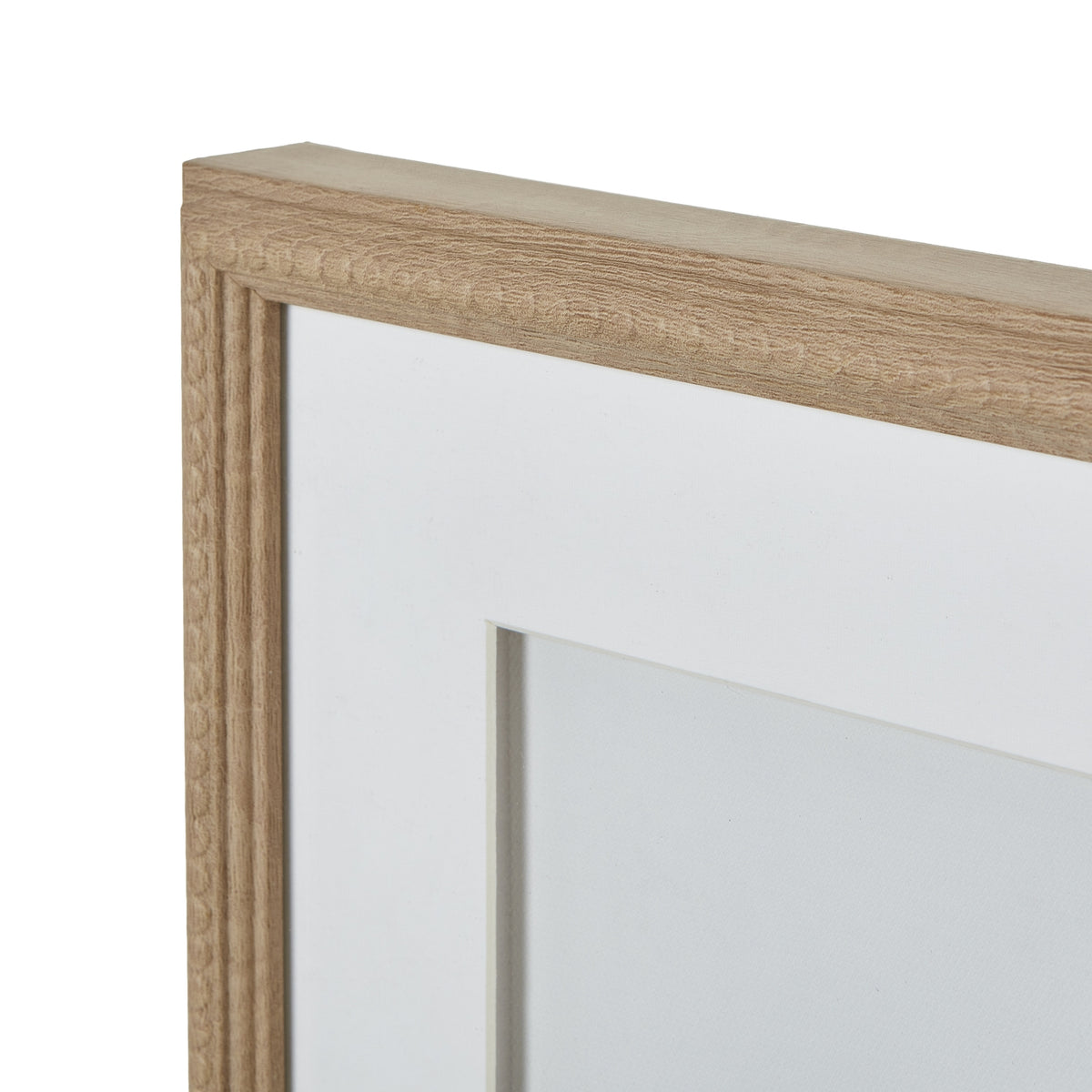 Close view of the frame's upper-left corner, with light wood-look grain, repeating bead-shaped trim and the white mount beneath.