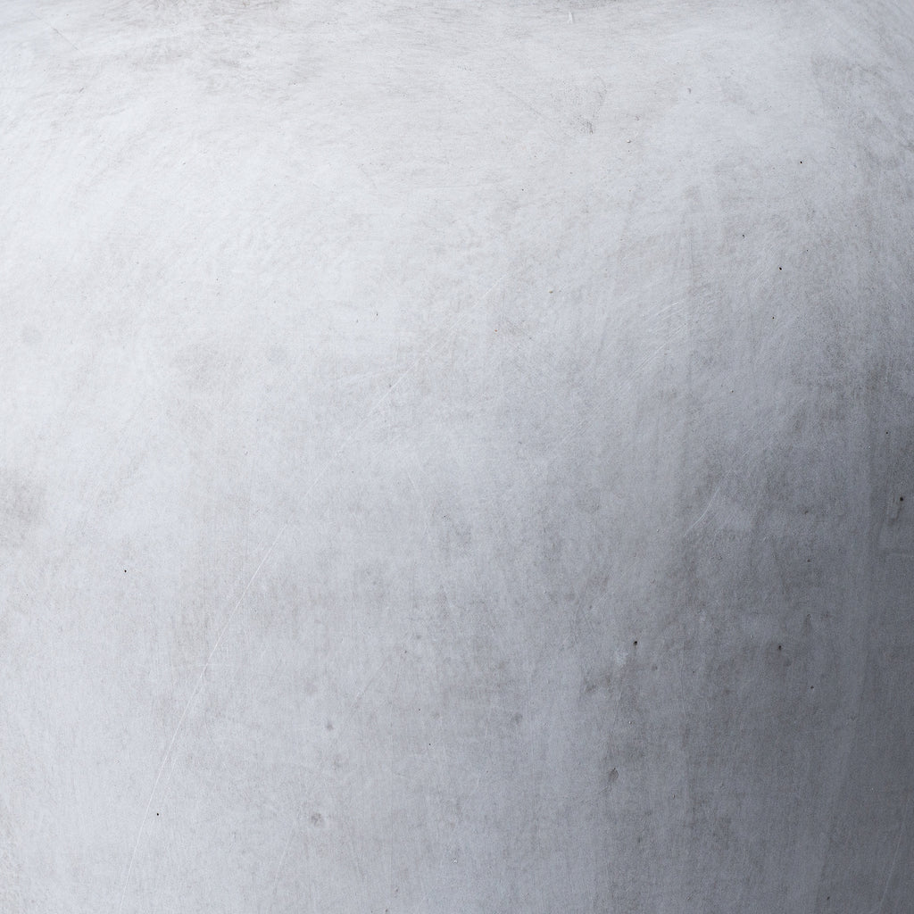 Close-up of the vase surface showing soft grey mottling, fine pale lines and small darker marks.