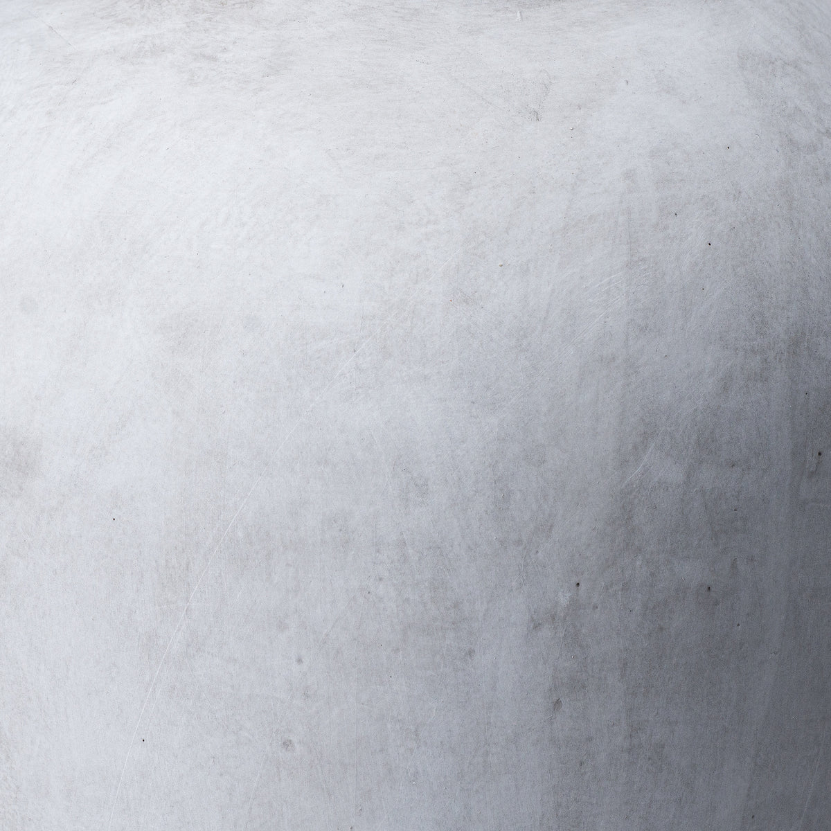 Close-up of the vase surface showing soft grey mottling, fine pale lines and small darker marks.