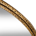Close-up of the upper frame curve, with small dark impressions across both gold-tone bands beside the reflective panel.