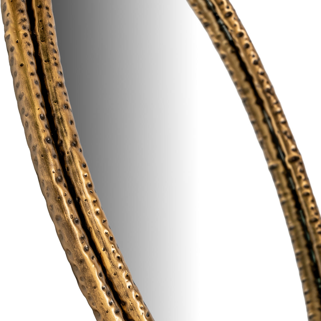 Angled close-up of the mirror's double gold-tone frame, showing dimpled impressions beside the reflective panel.