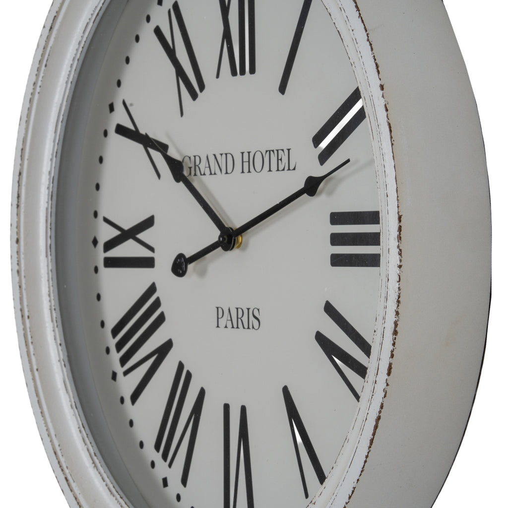 Angled close-up of the pale clock face, showing the shaped black hands and dark distressed marks along the white rim.