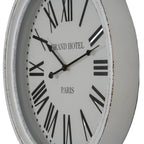 Angled close-up of the pale clock face, showing the shaped black hands and dark distressed marks along the white rim.