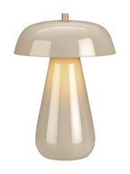 Full view of the beige dome table lamp with a warm golden glow beneath the shade and reflections along the tapered base.