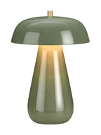 Green dome table lamp switched on, with a yellow glow beneath the shade and reflections down the tapered base.