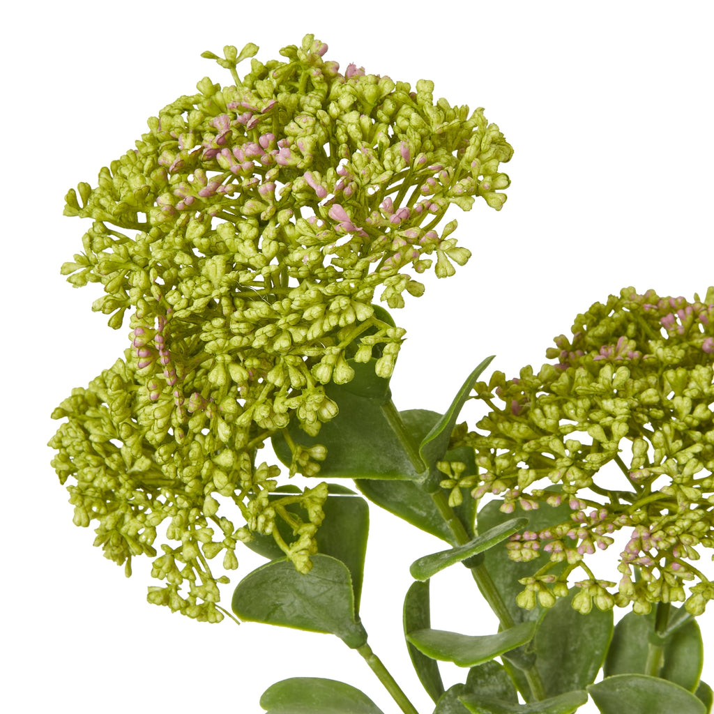 Close-up of tightly grouped green buds with scattered muted pink tips, above rounded green leaves on the artificial botanical spray.