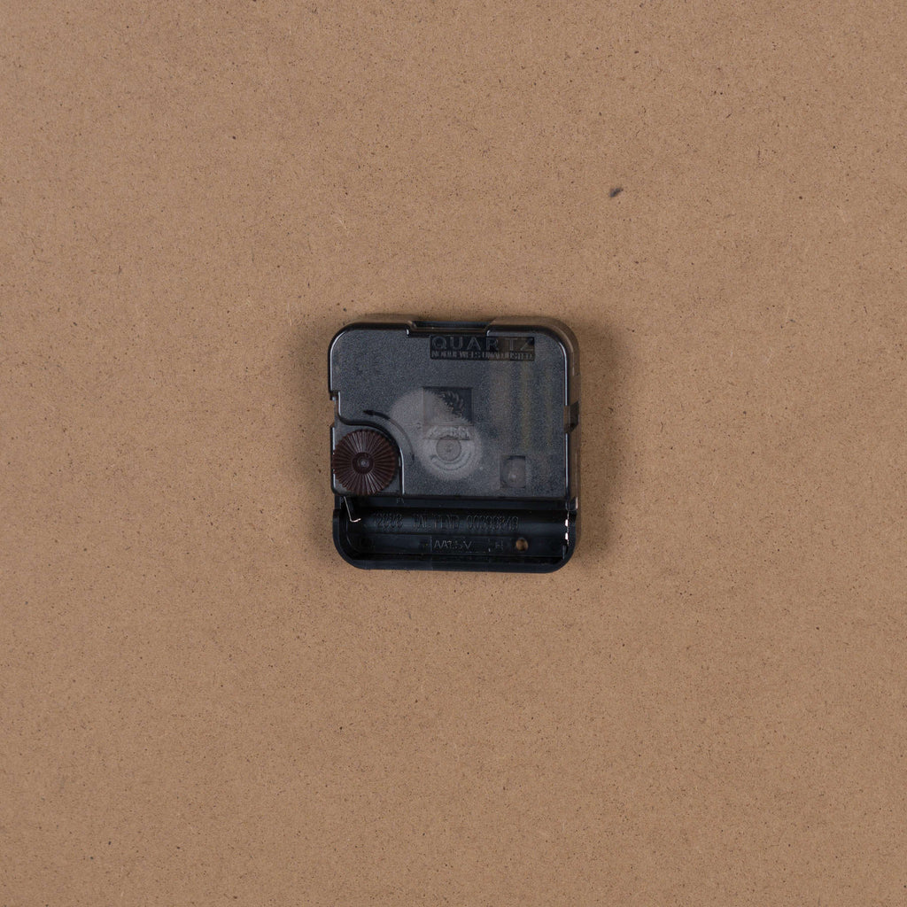 Rear close-up showing the black quartz movement and open battery compartment against the plain brown backing.