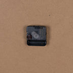 Rear close-up showing the black quartz movement and open battery compartment against the plain brown backing.