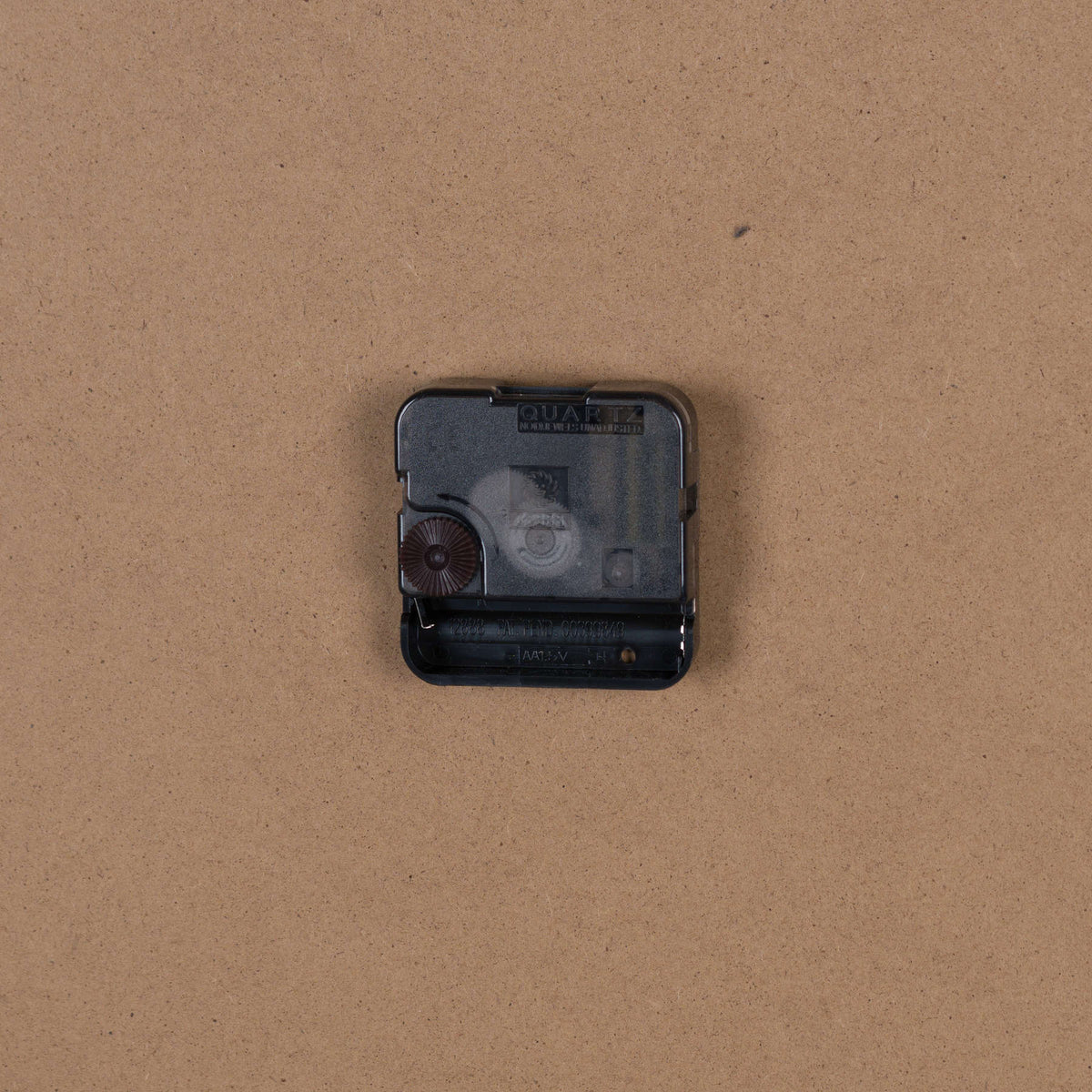 Rear close-up showing the black quartz movement and open battery compartment against the plain brown backing.