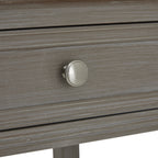 Close-up of a round silver-toned knob centred on a grey-washed drawer front with a rectangular moulded border.