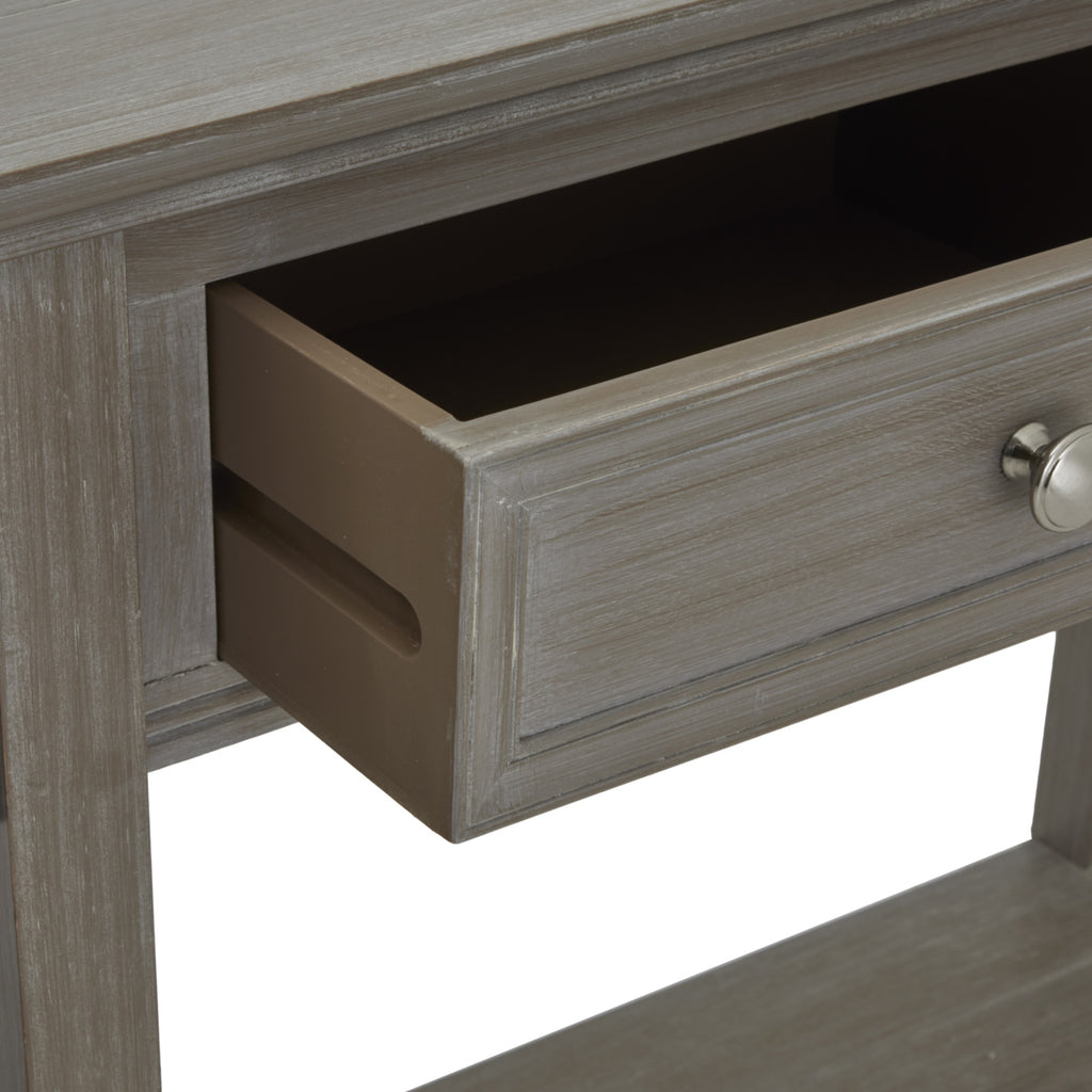 Close-up of a console drawer pulled open, showing its dark interior, brown side panel and framed grey front with a round silver-toned knob.