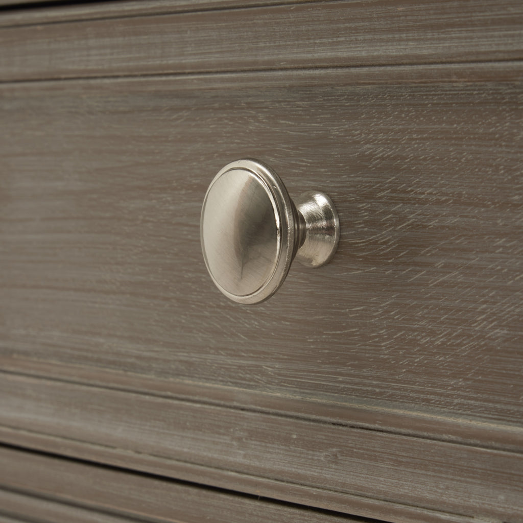 Close-up of the round silver-coloured drawer knob against the pale-streaked grey finish.