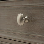 Close-up of the round silver-coloured drawer knob against the pale-streaked grey finish.